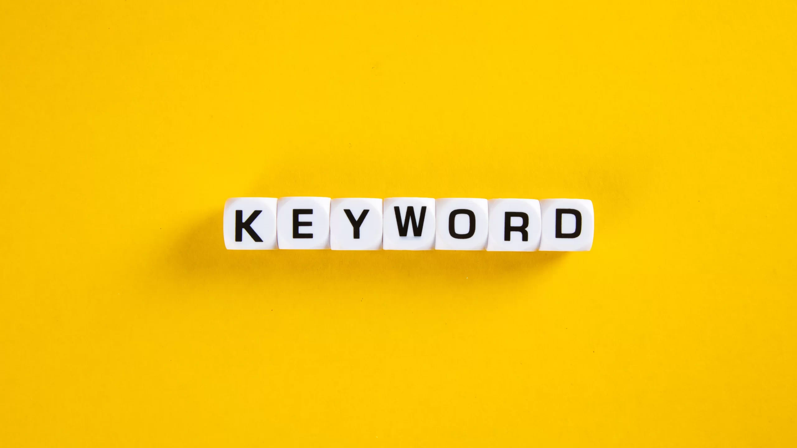 White dice on a yellow background. On the dice letters that form the word keyword.